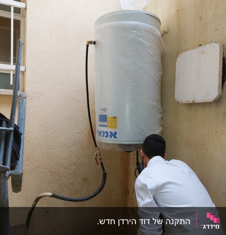 דוד שמש מותקן על קיר עם צינורות מחוברים